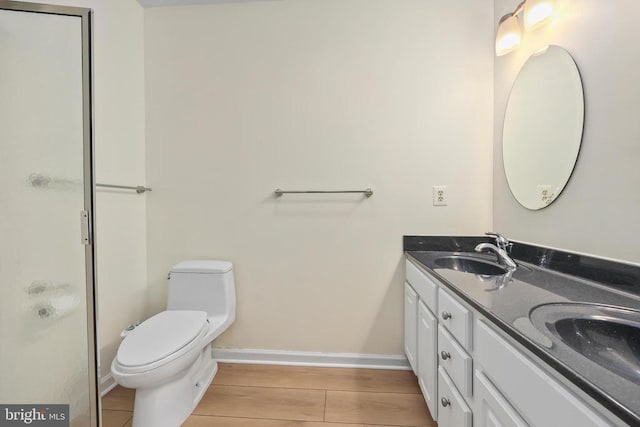 bathroom with a sink, baseboards, wood finished floors, and double vanity