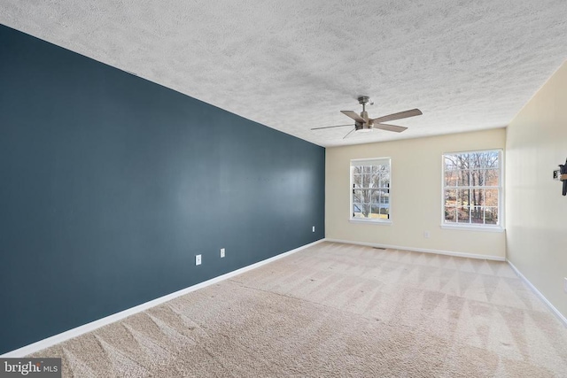 carpeted empty room featuring baseboards, a textured ceiling, and a ceiling fan