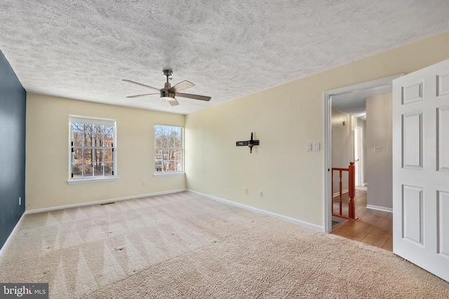 empty room featuring baseboards, carpet, a ceiling fan, and a textured ceiling