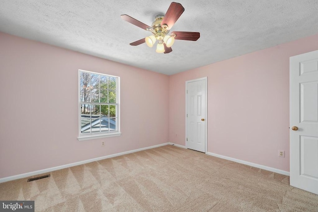 empty room featuring visible vents, a textured ceiling, carpet floors, baseboards, and ceiling fan