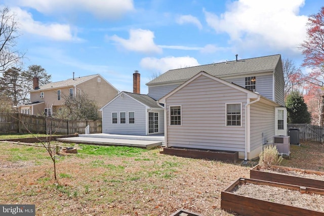 back of house featuring cooling unit, a wooden deck, a garden, a yard, and a fenced backyard