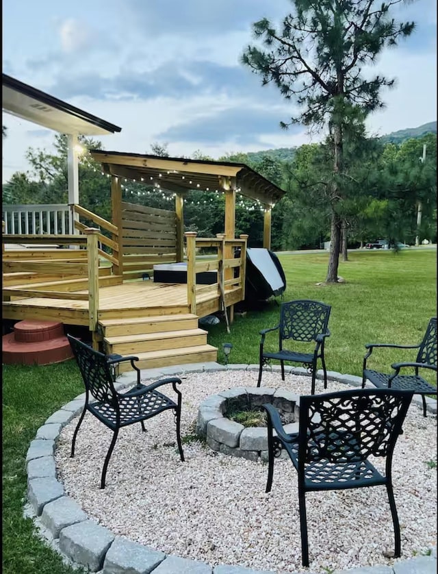 view of jungle gym with a lawn, a deck, a patio, and an outdoor fire pit