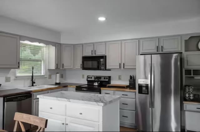 kitchen featuring stainless steel appliances, a center island, a sink, and gray cabinets