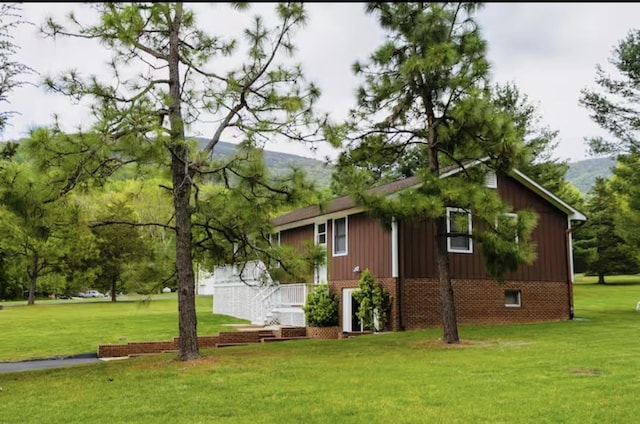 view of home's exterior featuring a lawn, brick siding, and a mountain view