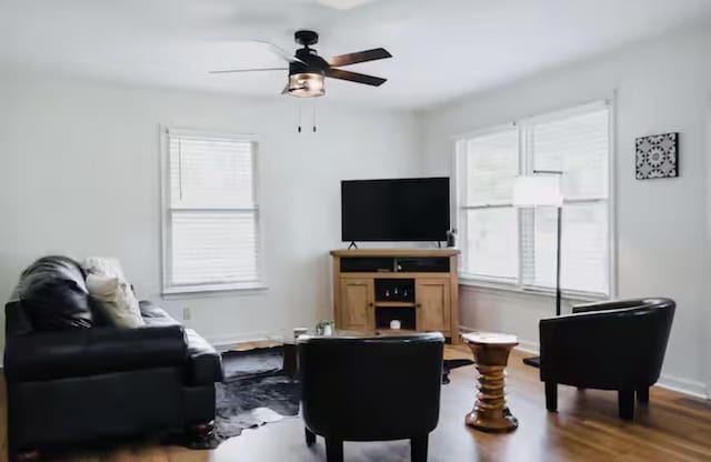 living area featuring baseboards, wood finished floors, and ceiling fan