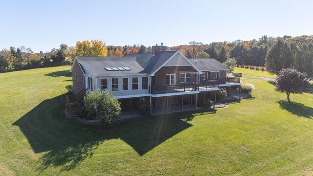 rear view of property with a wooden deck and a lawn