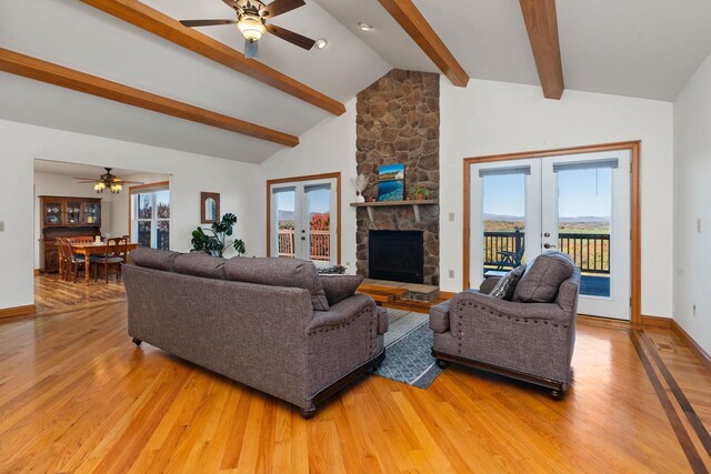 living room featuring hardwood / wood-style floors, a stone fireplace, french doors, and beamed ceiling