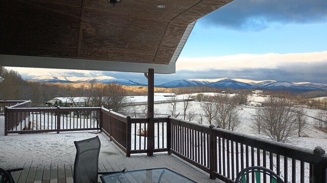 snow covered deck with a mountain view