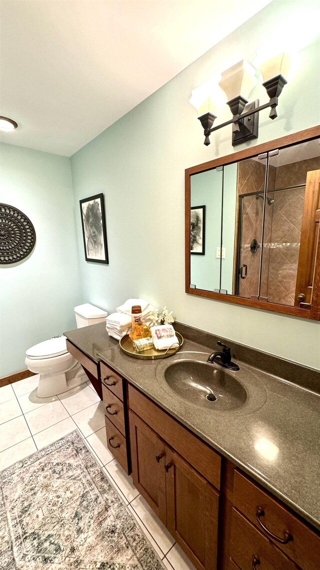 bathroom with vanity, toilet, tile patterned flooring, and a tile shower