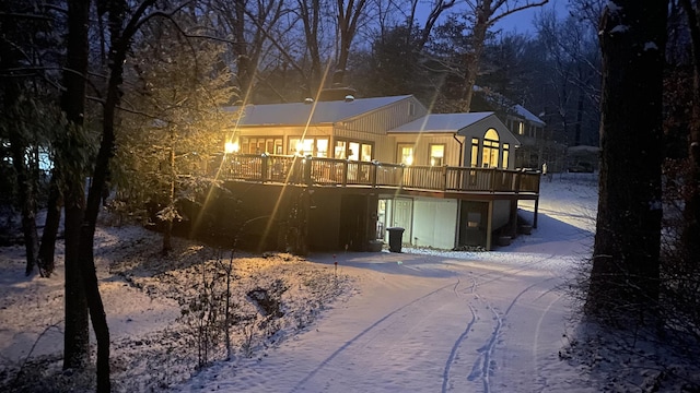 snow covered rear of property with a deck