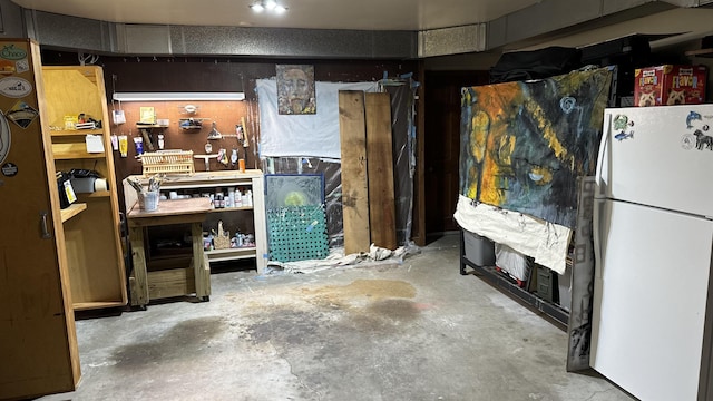 basement with white fridge, a fireplace, and a workshop area