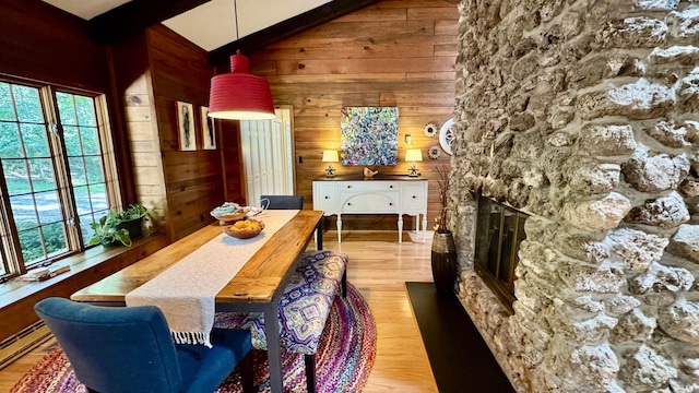 dining space with hardwood / wood-style floors, a fireplace, wood walls, beamed ceiling, and a baseboard heating unit