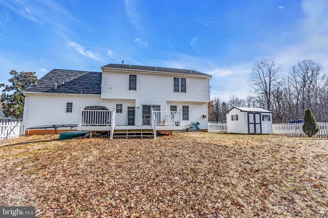 rear view of property featuring a deck and a storage unit