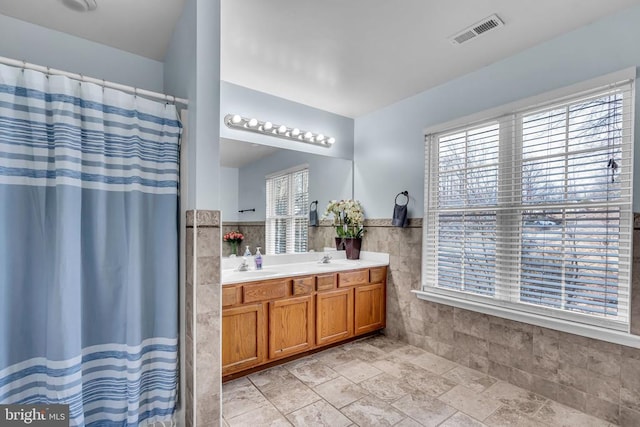 bathroom featuring a shower with curtain, plenty of natural light, tile walls, and vanity