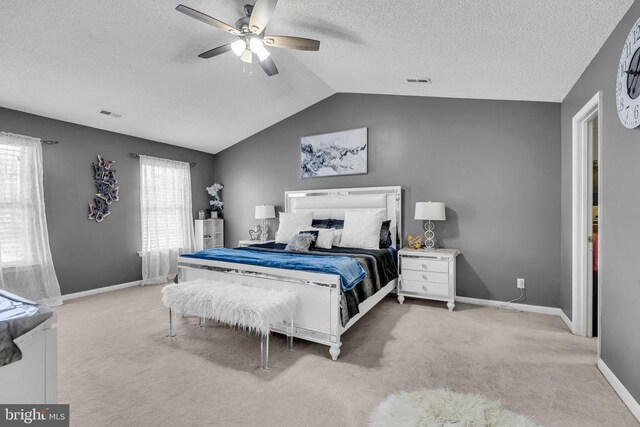 carpeted bedroom featuring a textured ceiling, vaulted ceiling, and ceiling fan