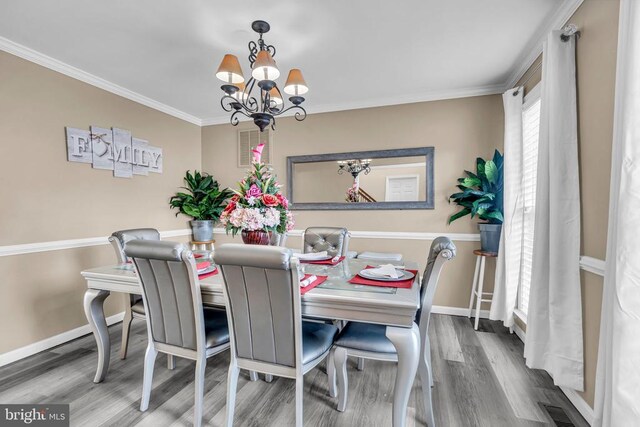 dining area with crown molding, hardwood / wood-style floors, and an inviting chandelier