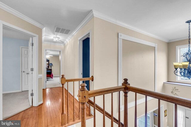 hallway featuring ornamental molding, hardwood / wood-style floors, and a notable chandelier