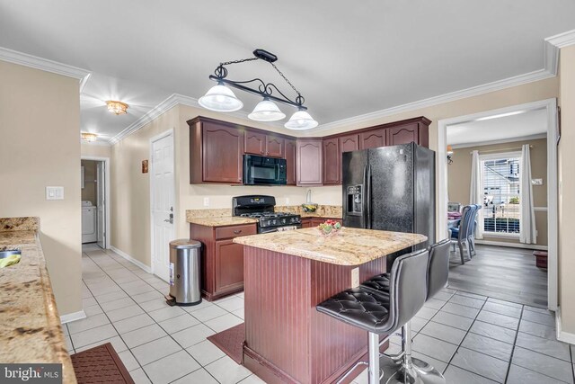 kitchen with light tile patterned floors, crown molding, hanging light fixtures, a center island, and black appliances