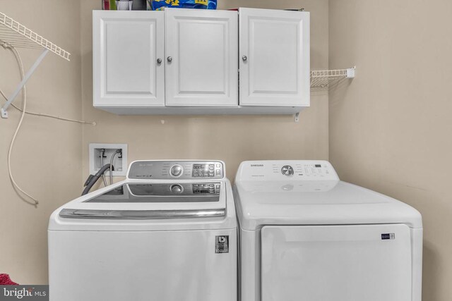 clothes washing area featuring washer and clothes dryer and cabinets