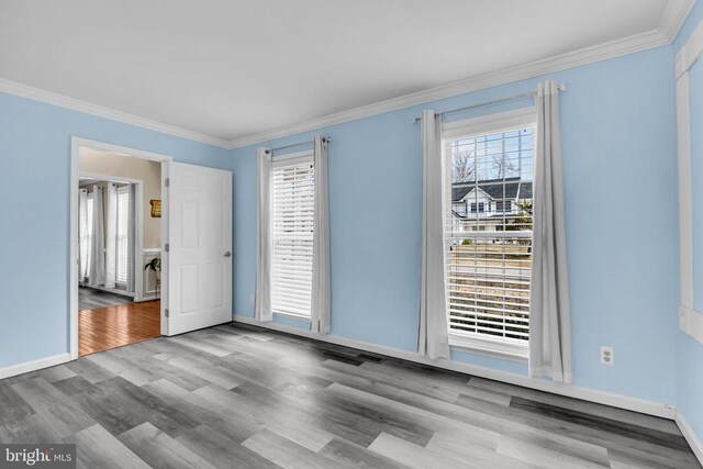 spare room with ornamental molding and light hardwood / wood-style flooring