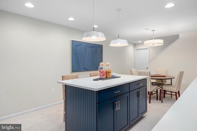 kitchen featuring blue cabinetry, decorative light fixtures, light carpet, and a kitchen island