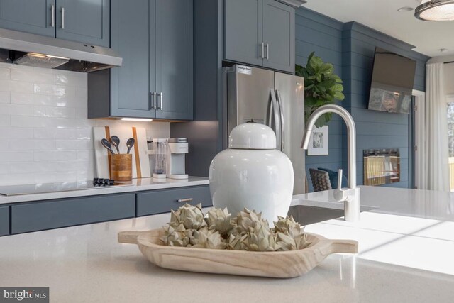 interior details with black electric stovetop, backsplash, and blue cabinets