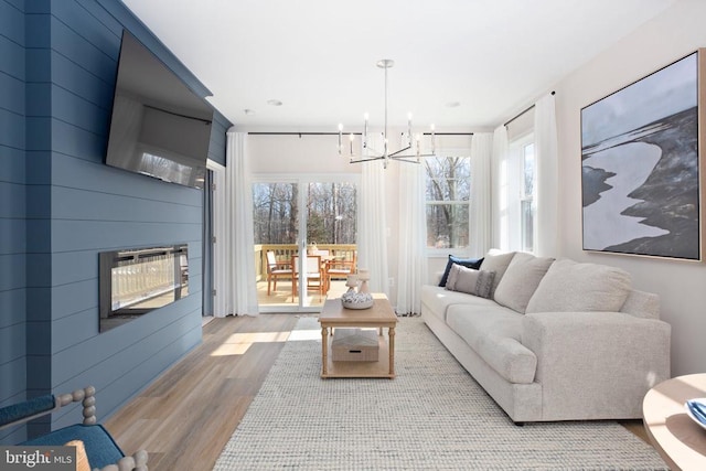 living room with hardwood / wood-style floors, a notable chandelier, and a large fireplace