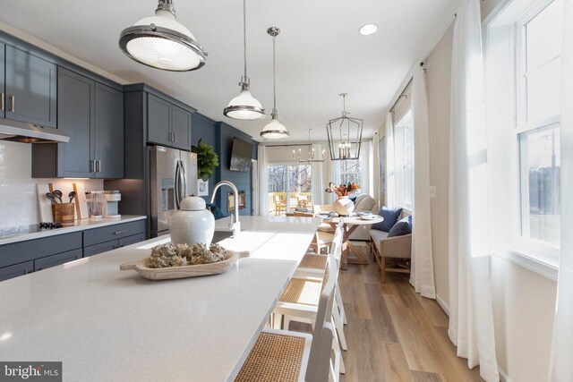 kitchen featuring pendant lighting, stainless steel fridge, a breakfast bar area, light hardwood / wood-style floors, and black gas stovetop