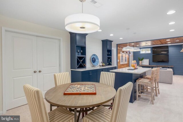 dining space featuring light colored carpet and wooden walls