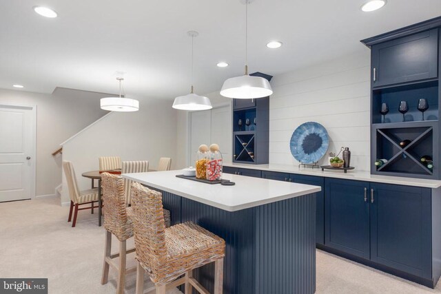 kitchen with pendant lighting, a center island, blue cabinetry, and light carpet