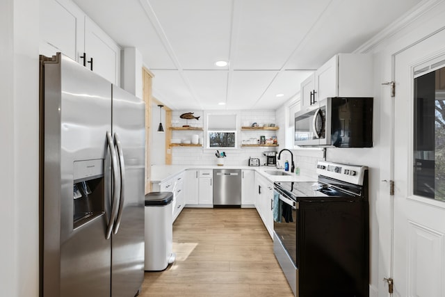 kitchen with light wood-type flooring, decorative backsplash, stainless steel appliances, white cabinetry, and open shelves