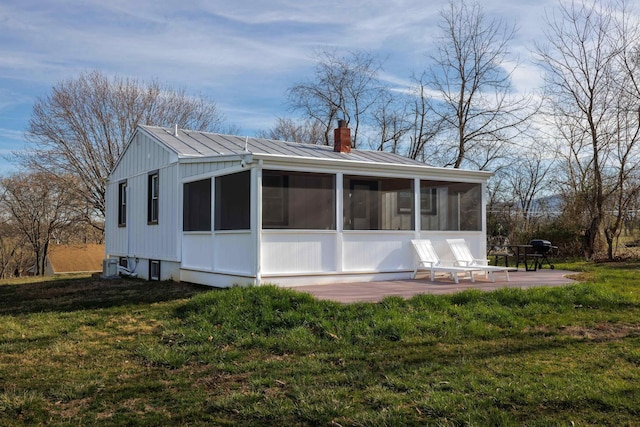 rear view of property featuring a patio, a yard, a sunroom, a chimney, and central air condition unit