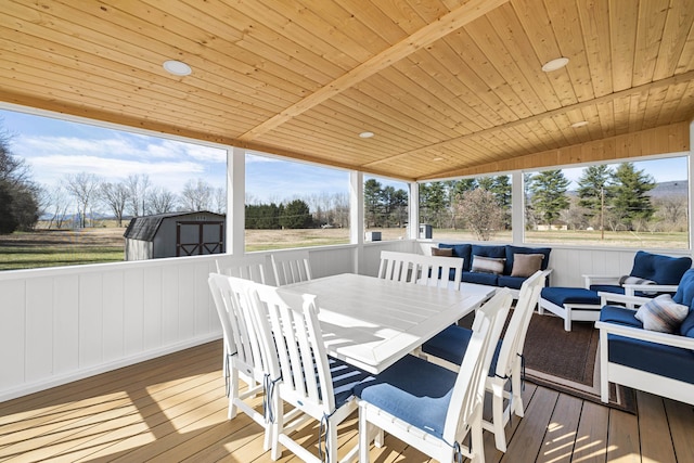wooden deck featuring an outdoor hangout area, an outbuilding, outdoor dining space, and a shed