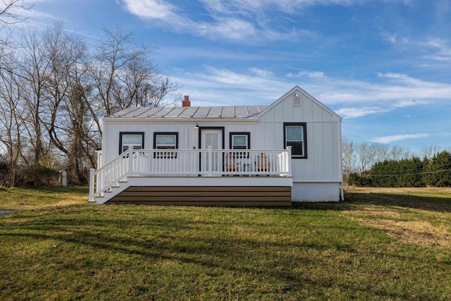 view of front of home with a front lawn, a chimney, board and batten siding, and metal roof