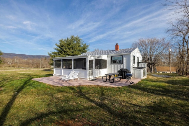 rear view of property with a patio area, a yard, and a sunroom