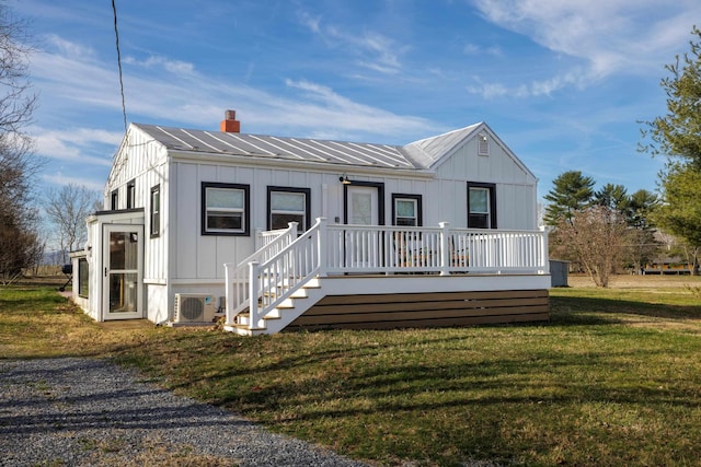 view of front of home featuring ac unit, a front lawn, board and batten siding, metal roof, and a chimney