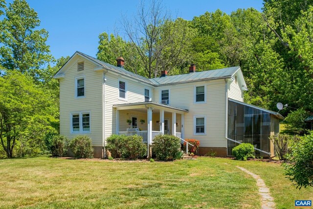 rear view of property featuring a yard, a sunroom, and covered porch