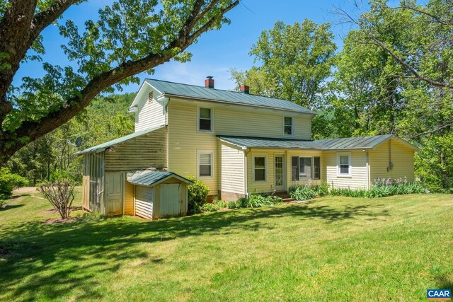 rear view of property featuring a shed and a lawn