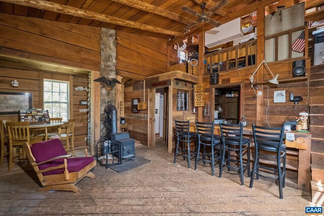 dining room with beam ceiling, wooden walls, wooden ceiling, and a wood stove