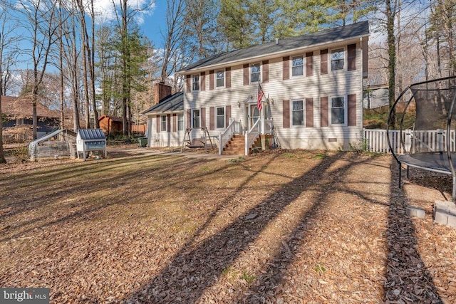 view of front of house with crawl space, a trampoline, and a chimney