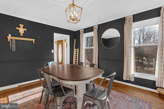 dining space featuring ornamental molding, a chandelier, baseboards, and wood finished floors