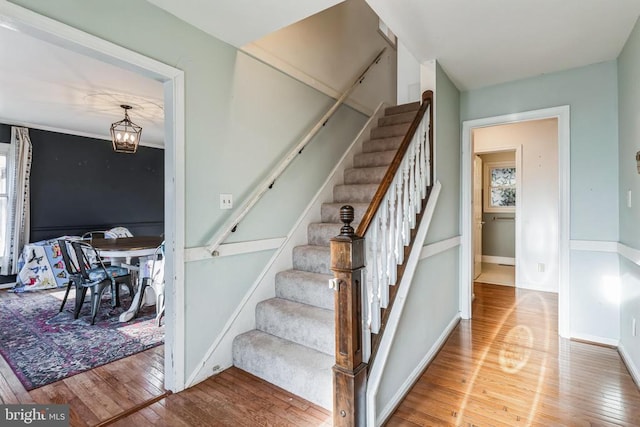 stairs featuring hardwood / wood-style flooring, baseboards, and an inviting chandelier