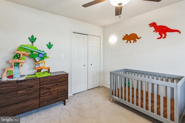 bedroom featuring light carpet, a closet, a nursery area, and a ceiling fan