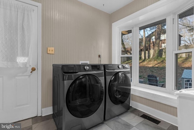 clothes washing area with washer and dryer, laundry area, visible vents, and baseboards