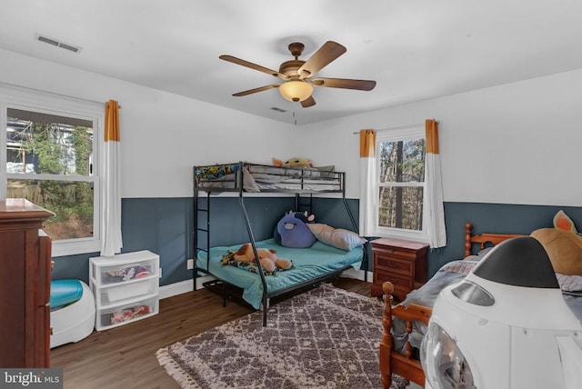 bedroom with wood finished floors, visible vents, ceiling fan, and multiple windows