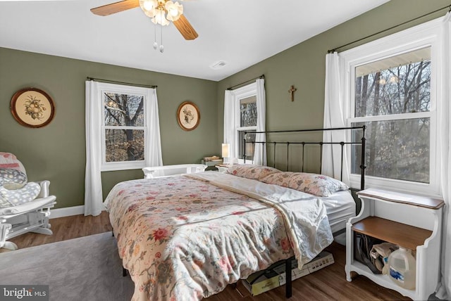 bedroom featuring a ceiling fan, baseboards, visible vents, and wood finished floors