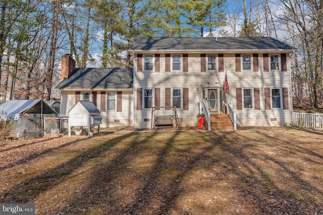 colonial-style house featuring an outbuilding, crawl space, a chimney, and fence