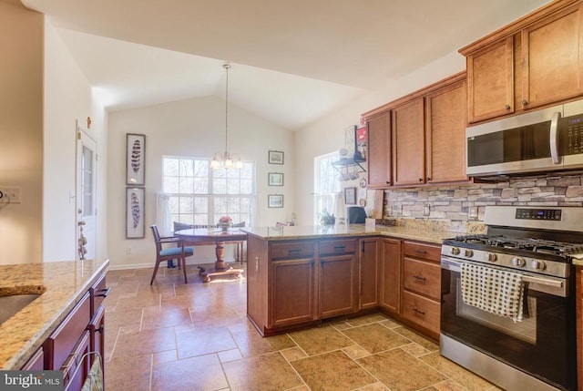 kitchen featuring stone tile floors, lofted ceiling, a peninsula, an inviting chandelier, and appliances with stainless steel finishes