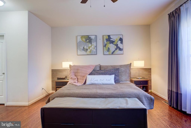 bedroom with a ceiling fan, wood finished floors, and baseboards