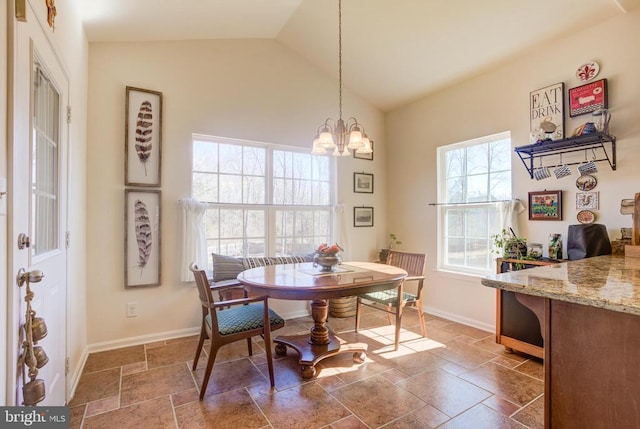 dining room featuring vaulted ceiling, stone tile floors, a notable chandelier, and baseboards